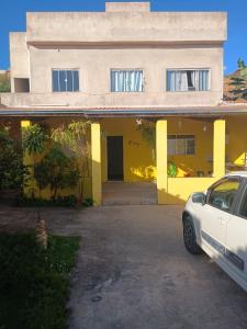 a white car parked in front of a yellow house at Casa Amarela in Pouso Alegre