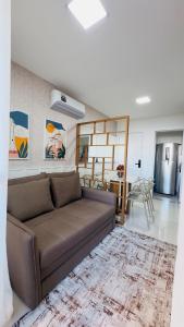 a living room with a brown couch and a kitchen at Seu refúgio com vista para o mar in Vila Velha
