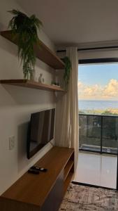a living room with a television and a large window at Seu refúgio com vista para o mar in Vila Velha