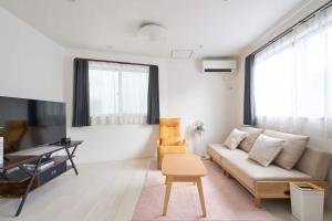 a living room with a couch and a desk and a tv at 東京Dong house in Wada