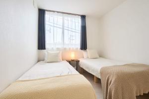 two beds in a room with a window at 東京Dong house in Wada