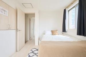 a white bedroom with a bed and a window at 東京Dong house in Wada