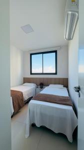 two beds in a room with a window at Seu refúgio com vista para o mar in Vila Velha