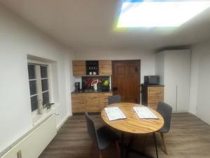 a dining room with a table and chairs and a kitchen at Forsthaus Neudorf - Eschenblick in Harzgerode +3 photos