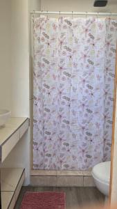 a bathroom with a shower curtain with a toilet at Matapalo Hosting in Savegre