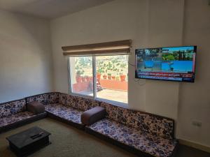 a living room with a couch and a flat screen tv at بيت اطلالة الوادي in Ajloun