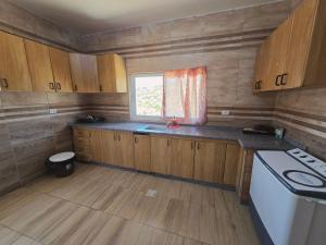 a small kitchen with wooden cabinets and a window at بيت اطلالة الوادي in Ajloun
