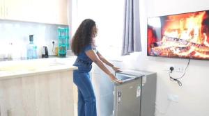a woman standing in a kitchen in front of a tv at The Elite havens in Nairobi