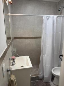 a bathroom with a white shower curtain and a sink at San Vicente in Olavarría