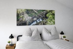 a bed with white pillows and a painting on the wall at Quartier No 7 Salzburg Süd Apartments in Grödig