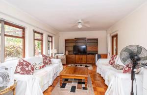 a living room with white couches and a tv at Sunset Nest in Meadowridge