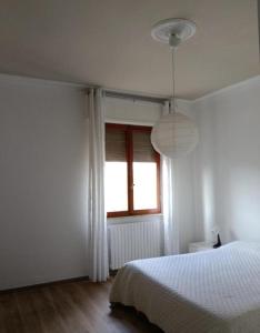 a white bedroom with a bed and a window at Casa Serena in Carrara