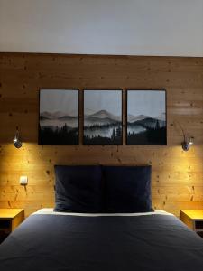 a bedroom with a bed with four pictures on the wall at Les Hauts du Lac in Gérardmer