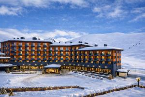 a hotel in the snow with snow covered mountains at Premium New Gudauri Apartments with Balcony & Gondola Views in Gudauri