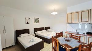 a room with three beds and a table and a kitchen at ARILEO ROOMs in Himare