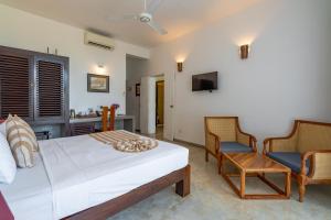 a bedroom with a bed and two chairs at Tartaruga Beach Unawatuna in Unawatuna