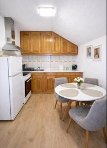 a kitchen with a table and a white refrigerator at Stan na dan Bumbar in Kostajnica +23 photos