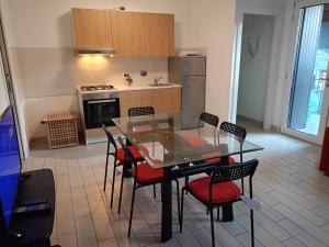 a kitchen with a glass table and chairs at Corte Don Bosco 4 in Monfalcone