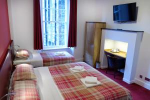 a room with two beds and a desk and a television at Regent House Hotel - City Centre Hotel in Edinburgh