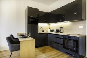 a kitchen with black appliances and a table and a chair at Calmora apartment Optická WiFi Klimatizace Balkon Nespresso in Komárov