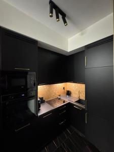 a black kitchen with a sink and a microwave at Moon Luxury Apartment - Jacuzzi & Sauna in Wałbrzych +21 photos