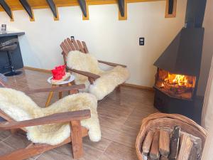 a living room with two chairs and a fireplace at Chalés Sol da Serra in Rio Rufino