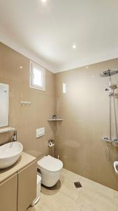 a bathroom with a white toilet and a sink at ARILEO ROOMs in Himare
