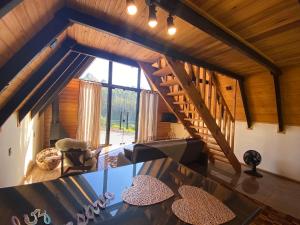 a living room with a glass table and a staircase at Chalés Sol da Serra in Rio Rufino