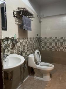 a bathroom with a toilet and a sink at Mughal Empire Hotel Pvt ltd in Pātan