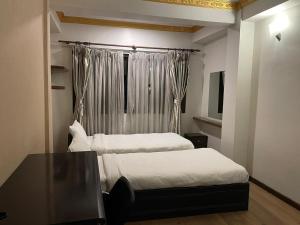 a bedroom with two beds and a table and a window at Mughal Empire Hotel Pvt ltd in Pātan