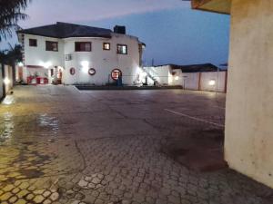 an empty parking lot in front of a white building at July 16th hotel and event centre in Alagbado