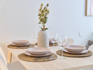 a table with plates and glasses and a vase with flowers at Beautiful and Spacious Studio in Helsinki in Helsinki
