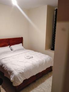 a small bedroom with a bed with white sheets at jjsuites in Athi River +3 photos