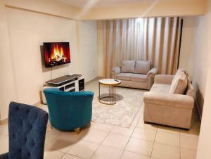 a living room with a couch and chairs and a tv at jjsuites in Athi River