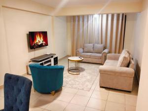 a living room with a couch and chairs and a tv at jjsuites in Athi River