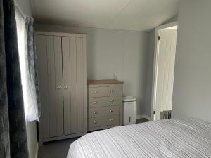 a bedroom with a bed and a dresser at Alberta holiday park in Whitstable +20 photos