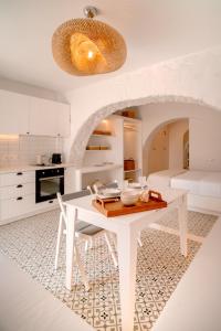 a white kitchen with a white table and chairs at Suite Amalaya Κατώι in Kithnos +13 photos