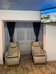 two chairs in a waiting room with a flat screen tv at Woodxury in Petrila
