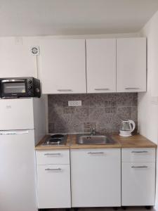 a kitchen with white cabinets and a sink and a microwave at Studio BIANCA in Kotor