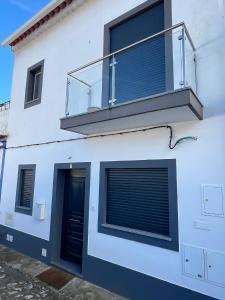 a white building with a balcony and a door at A Janela do Cantinho in Reguengos de Monsaraz