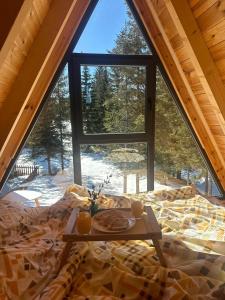 a bed with a tray of food on it in front of a window at Villa Aleksandra in Žabljak