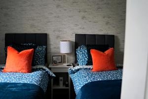 two beds with blue and orange pillows in a bedroom at Kirkhill Cottage B&B in Crossmichael