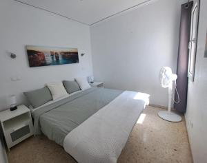 a white bedroom with a bed and a lamp at Appartement El Palmar Denia in Denia +25 photos