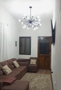 a living room with a brown couch and a chandelier at Arrendamientos portillo in Puerto Barrios