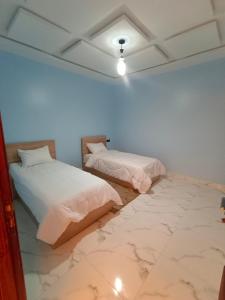 two beds in a room with a marble floor at شقق تاج الداخلة in Dakhla