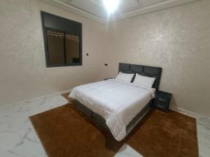 a bedroom with a bed with white sheets and a mirror at شقق تاج الداخلة in Dakhla +5 photos