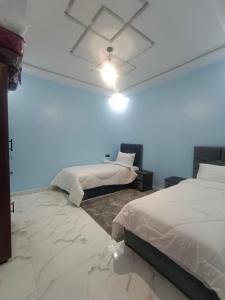 a bedroom with two beds and a ceiling fan at شقق تاج الداخلة in Dakhla