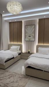 a bedroom with two beds and a chandelier at شقه ثلاث غرف بحي المروه in Jeddah