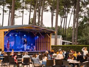 a group of people sitting at tables in front of a stage at Les dunes de contis- landes in Saint-Julien-en-Born