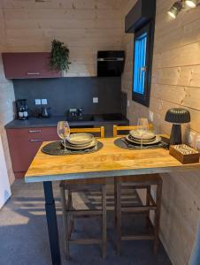 a kitchen with a wooden table with plates and wine glasses at Chic and Chill Guest House, gite Safari in Vallon-Pont-dʼArc